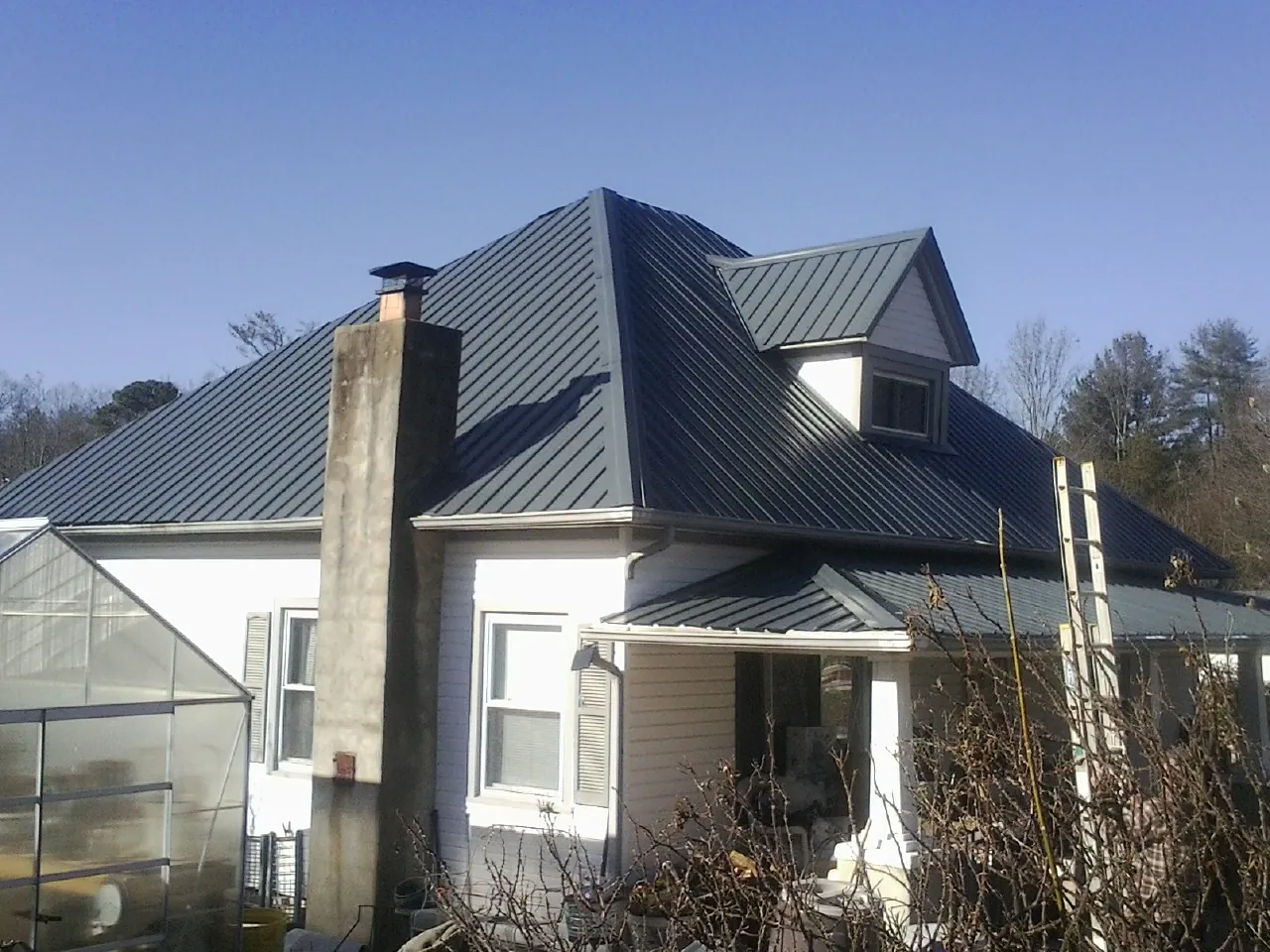 Dark blue standing seam metal roof on a white farmhouse with dormer — Slate & Tile Roof Repair by Roofing Brothers in Egg Harbor