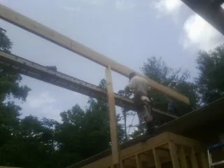 Carpenter setting a ridge beam over a new addition frame — Ice Dam Removal by Roofing Brothers in Egg Harbor
