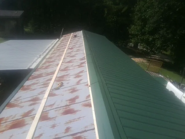 Old rusted panels beside newly installed green metal roofing — Wind Damage Roof Repair by Roofing Brothers in Egg Harbor