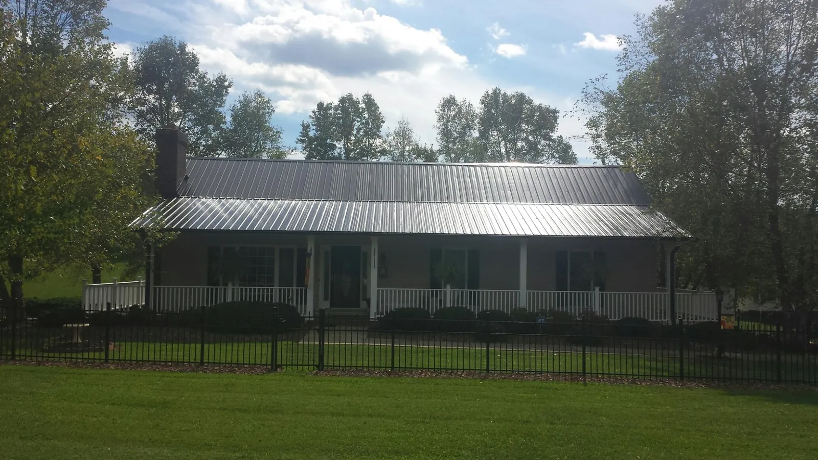 Gray metal roof on a brick ranch with a full width front porch — Gutter Guard Installation work by our crew in Egg Harbor