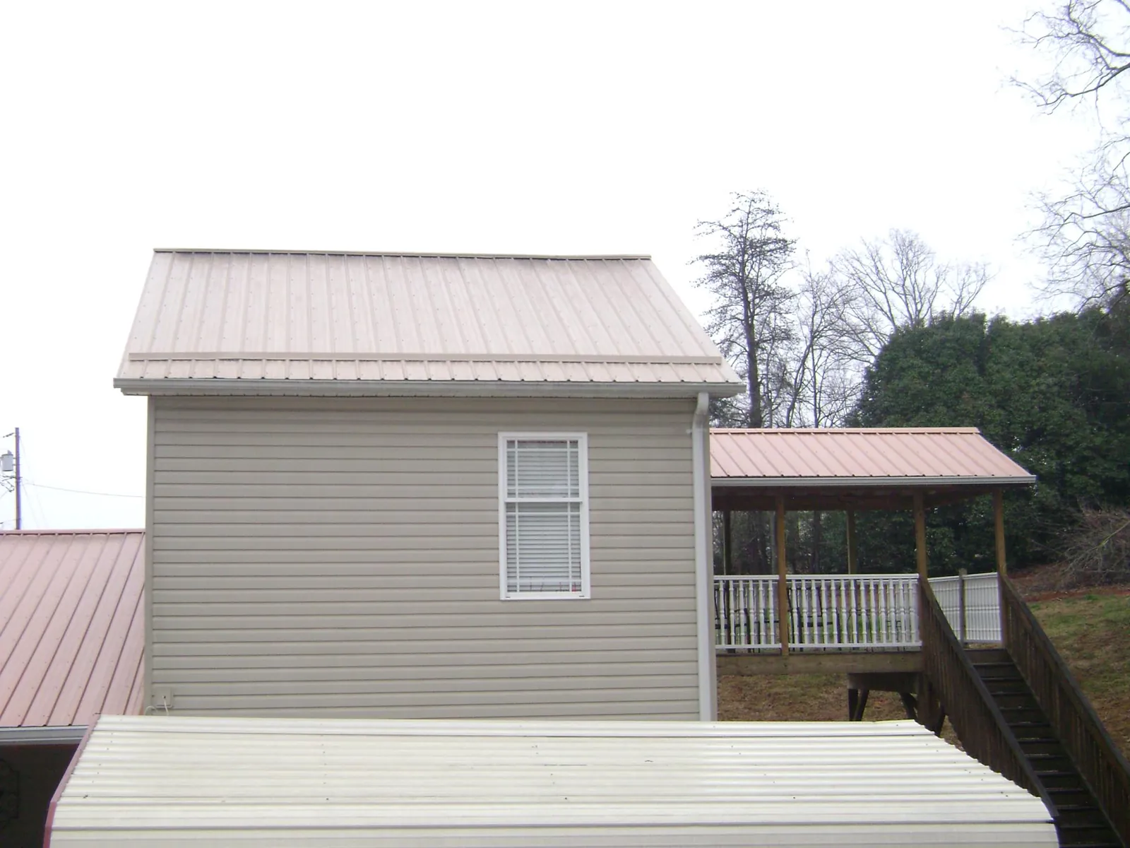 Tan metal roofs on a two story addition and attached porch, from a Roof Replacement job in Egg Harbor